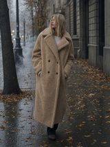 Vrouw in lange beige teddy winterjas op een koude herfststraat