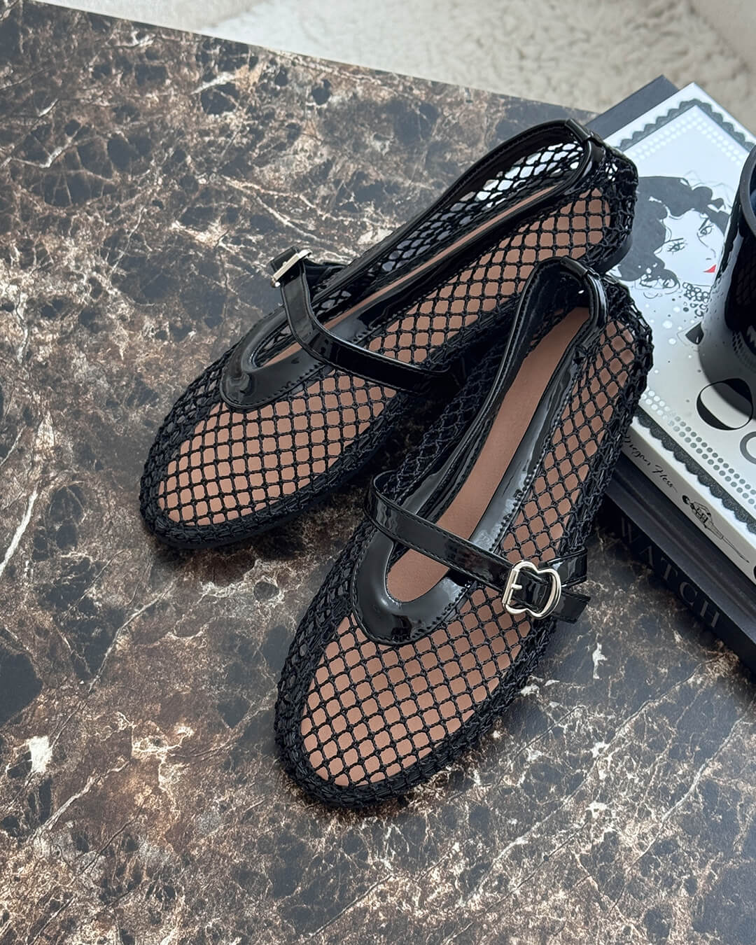zwarte mesh mary jane ballerina’s met glanzend bandje op marmerlook tafel