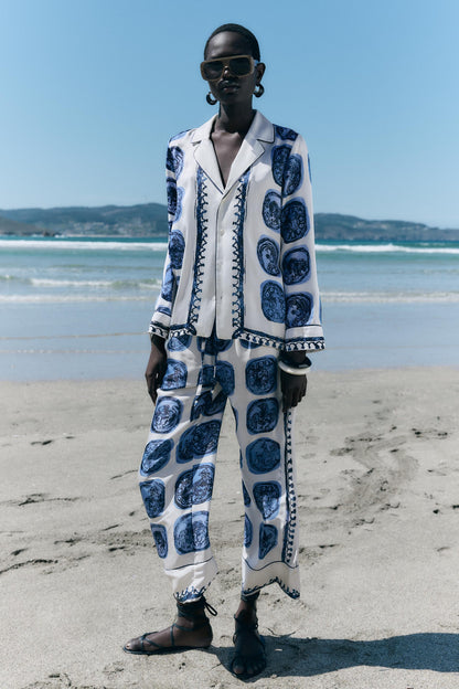 Een elegante set kleding met een wit en blauw patroon, geïnspireerd op Delfts Blauw, bestaande uit een blouse en bijpassende broek