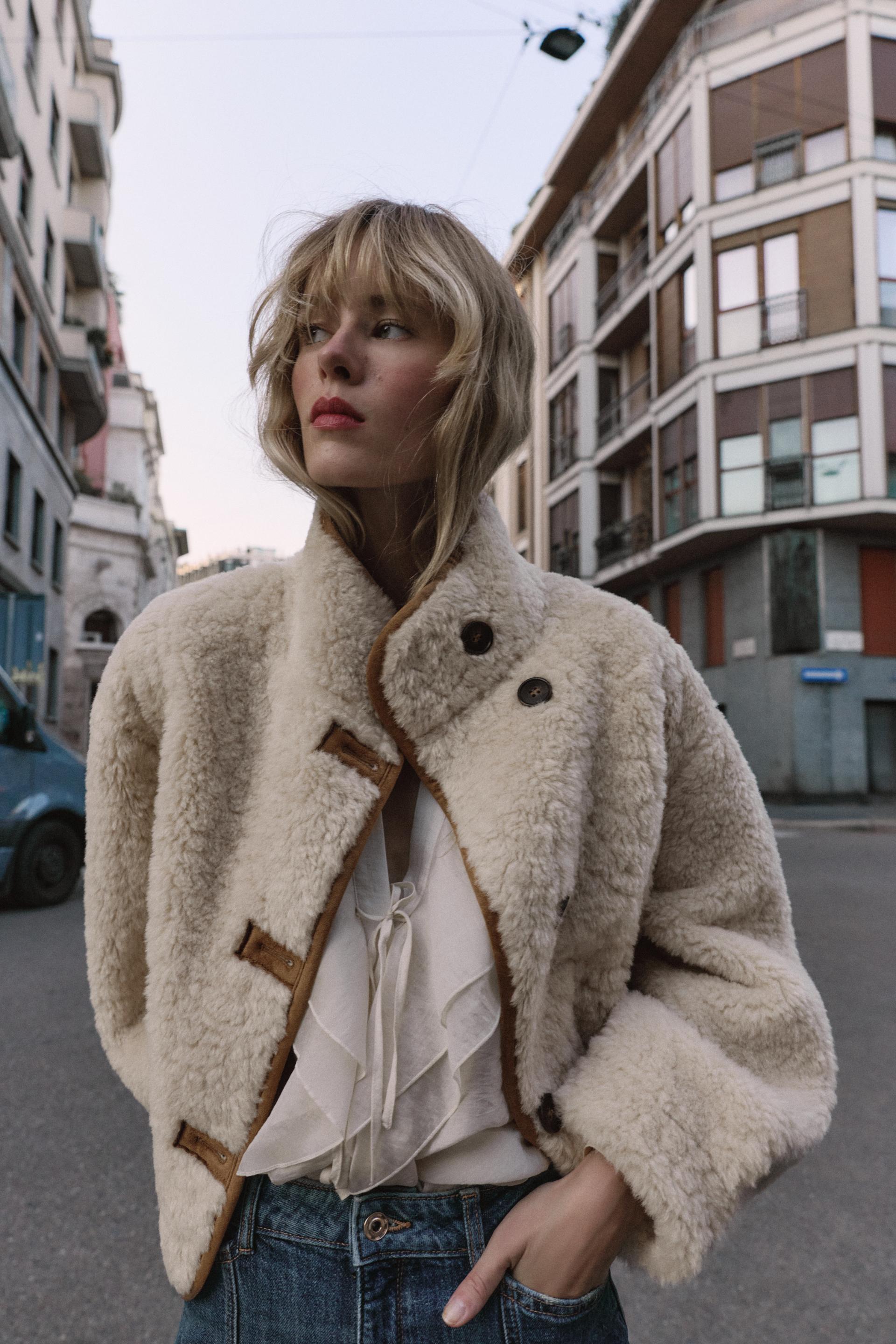 vrouw draagt beige teddy jas met knopen op straat