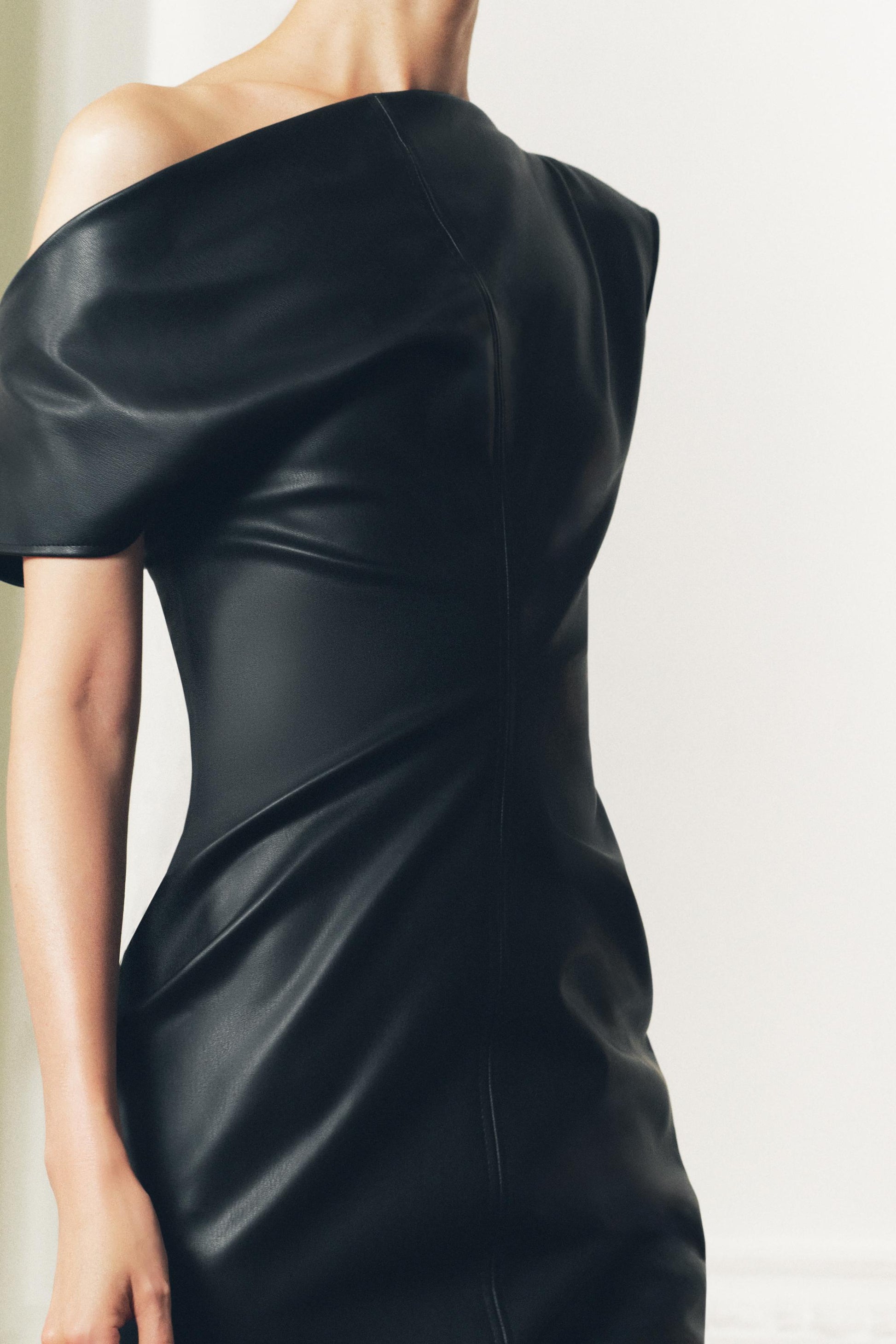 NoirDrape Faux Jurk in zwart faux-leather met asymmetrische details en draperend design, ideaal voor een chique avondlook