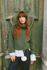 vrouw draagt groene gebreide coltrui met wijde mouwen en layered blouse eronder