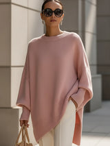 Roze oversized trui met vleermuismouwen, gedragen met een witte pantalon en een beige handtas