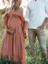 Zwangerschapsjurk off-shoulder roze buiten in het gras
