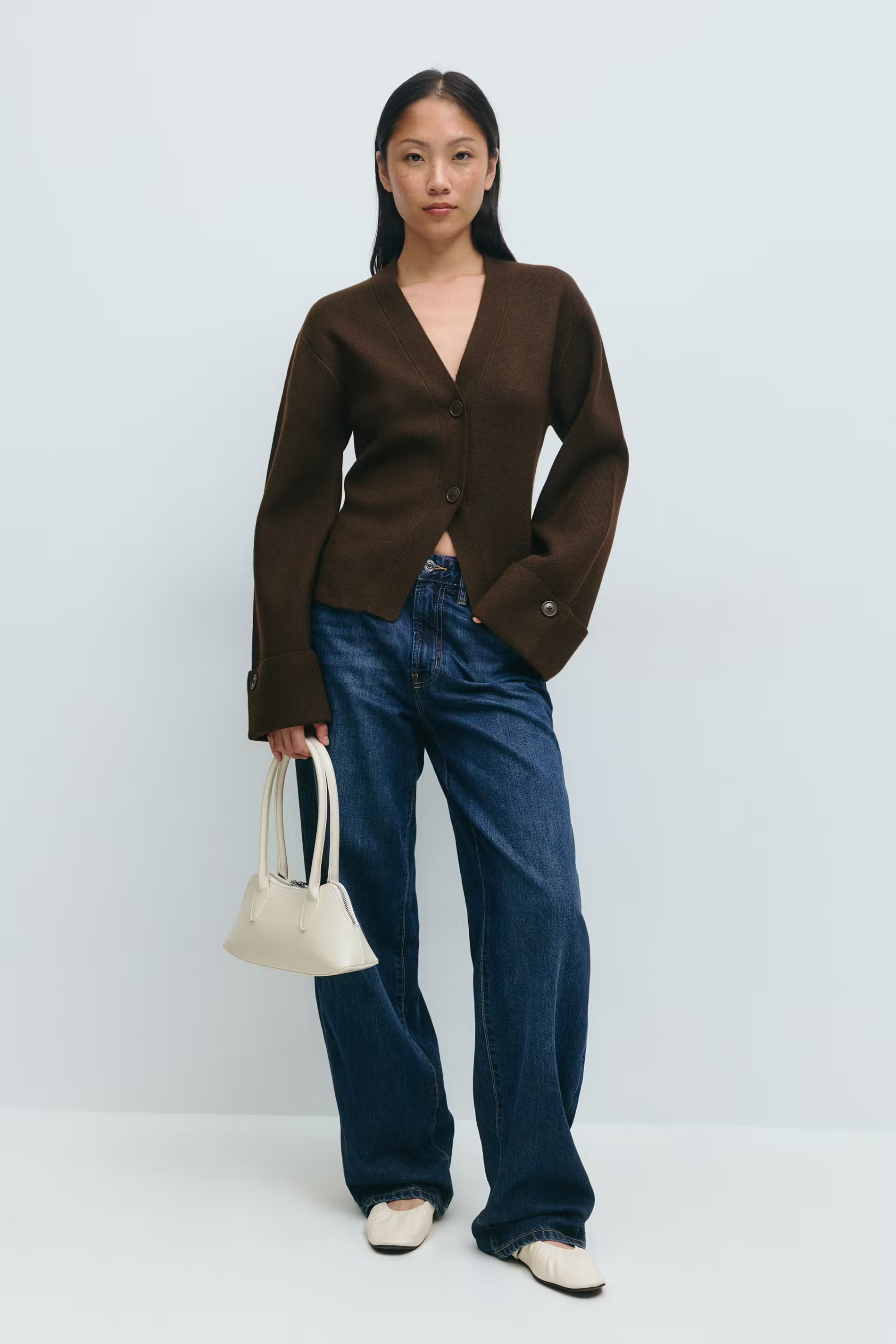 donkerbruine cardigan met jeans en witte tas