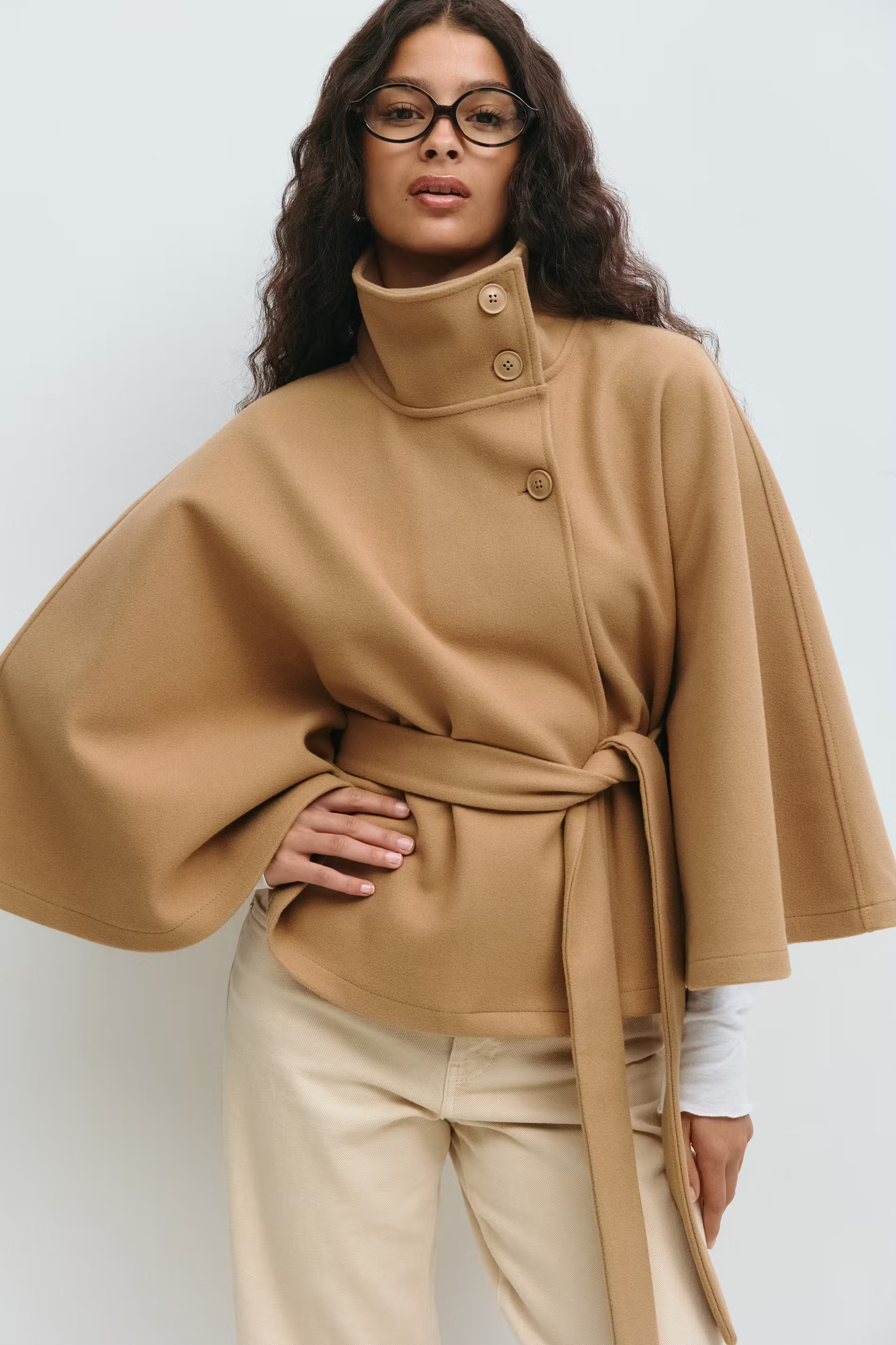 Beige cape jas met hoge kraag en knoopsluiting – close-up voorkant
