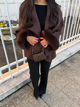 Donkerbruine winterjas met faux fur details aan de mouwen gecombineerd met laarzen