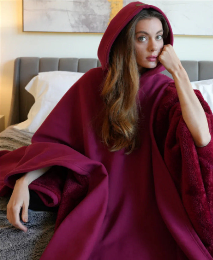 vrouw zit op bed in bordeauxrode hoodie blanket met teddyvoering