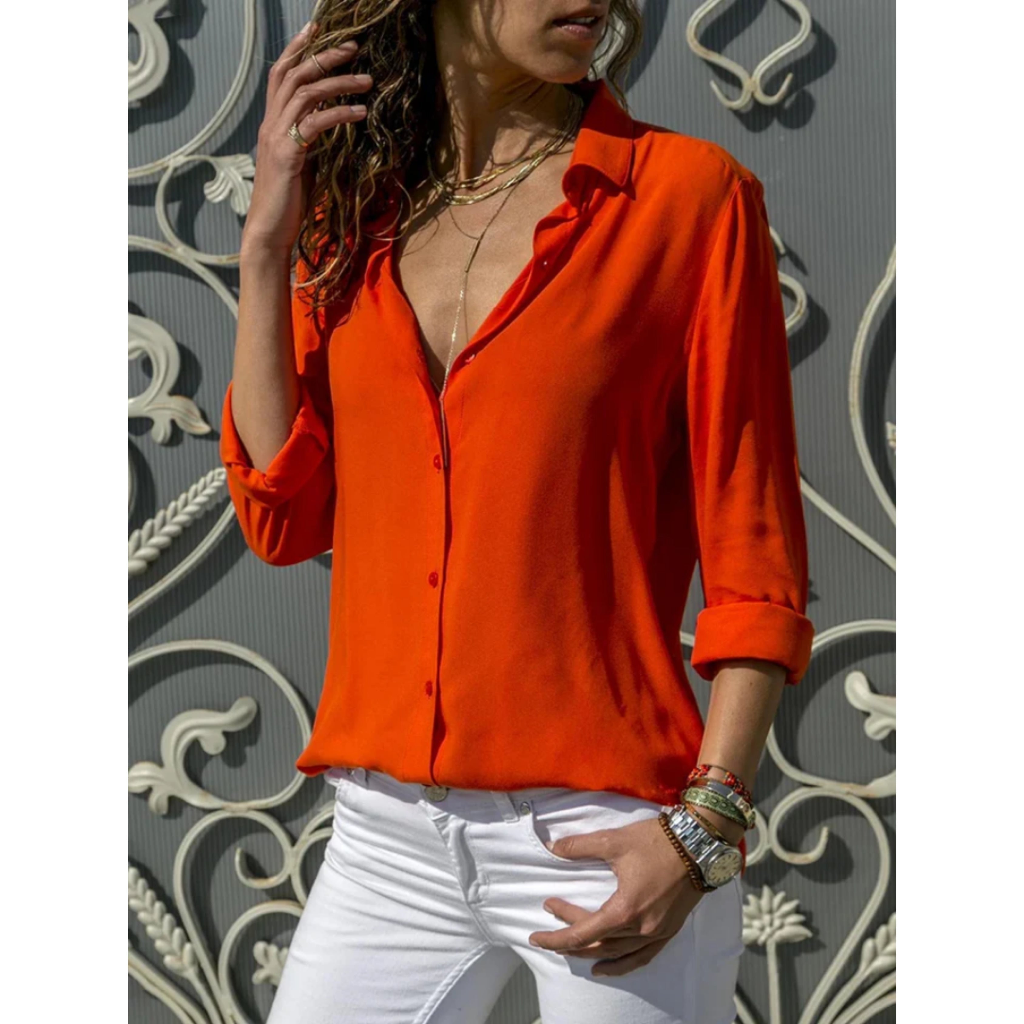 oranje blouse met opgerolde mouwen en knopen, gedragen met witte jeans