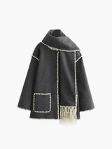 grijze cape-jas met geïntegreerde sjaal, contrasterende bies en franjes, productfoto voor dames