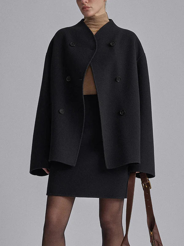 model draagt zwarte oversized jas met rok en coltrui