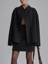 model draagt zwarte oversized jas met rok en coltrui