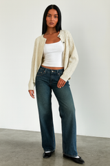 donkerblauwe mid waist wide-leg jeans gecombineerd met witte top en cardigan