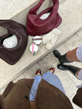 roze en bordeaux gevlochten schoudertassen op witte bank
