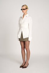 zijaanzicht van witte blouse met geplooid detail en manchet