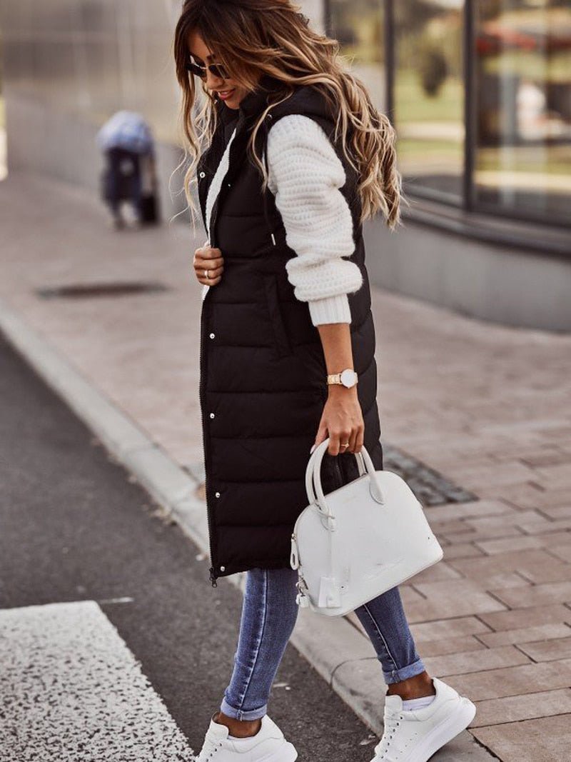 lange zwarte bodywarmer gestyled met witte sneakers en trui