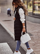 lange zwarte bodywarmer gestyled met witte sneakers en trui