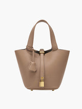 De Luna Lock Bag in 
taupe, met hoogwaardig vegan leer, gouden accenten en een metalen slot. Afmetingen: 16 x 20 x 19 cm