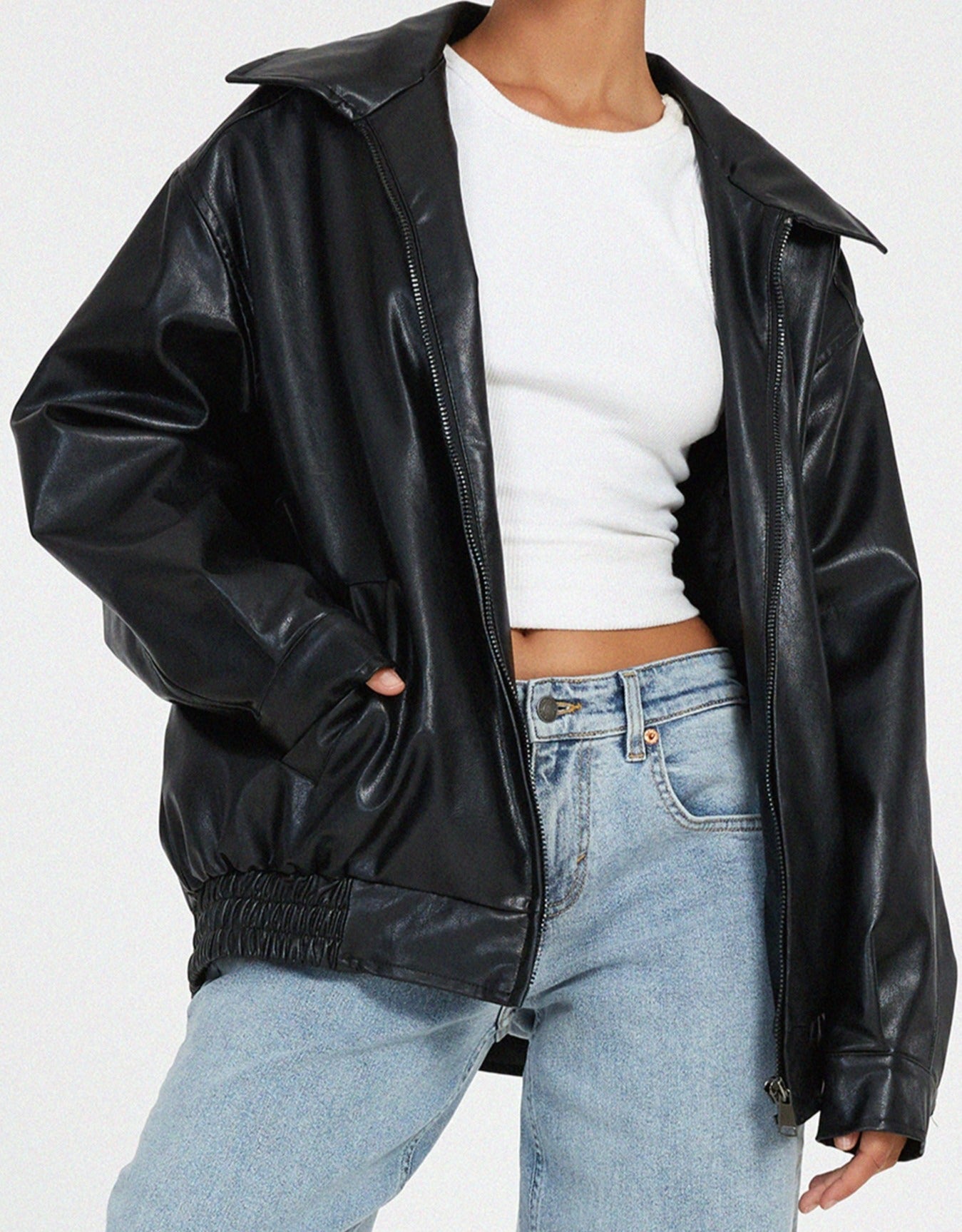 oversized zwarte leren jas met elastische taille, gedragen met wijde jeans