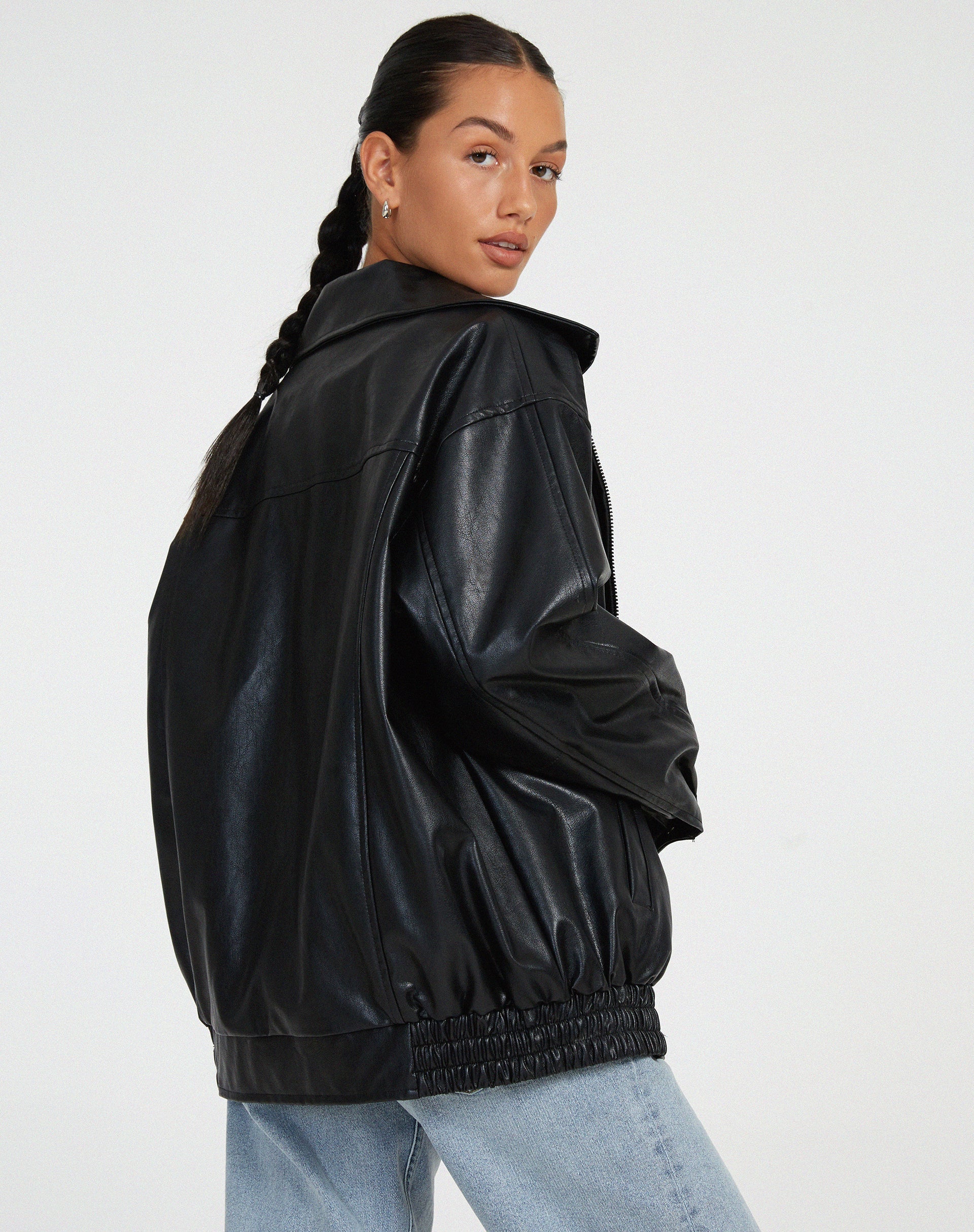 zwarte oversized leren jas gecombineerd met witte crop top en mom jeans