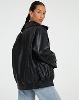 zwarte oversized leren jas gecombineerd met witte crop top en mom jeans