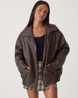 oversized bruine leren jas met rits en elastische taille, gedragen met geruite minirok