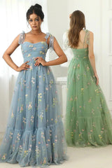 twee modellen in blauwe en groene geborduurde mesh jurken
