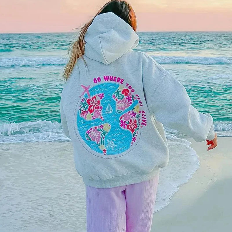 grijze hoodie met roze quote 'go where you feel alive' op het strand