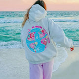 grijze hoodie met roze quote 'go where you feel alive' op het strand