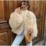 vrouw draagt beige fluffy imitatiebontjas met gevlochten tas en zonnebril