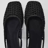 Dames draagt zwarte mesh slingback flats onder linnen outfit