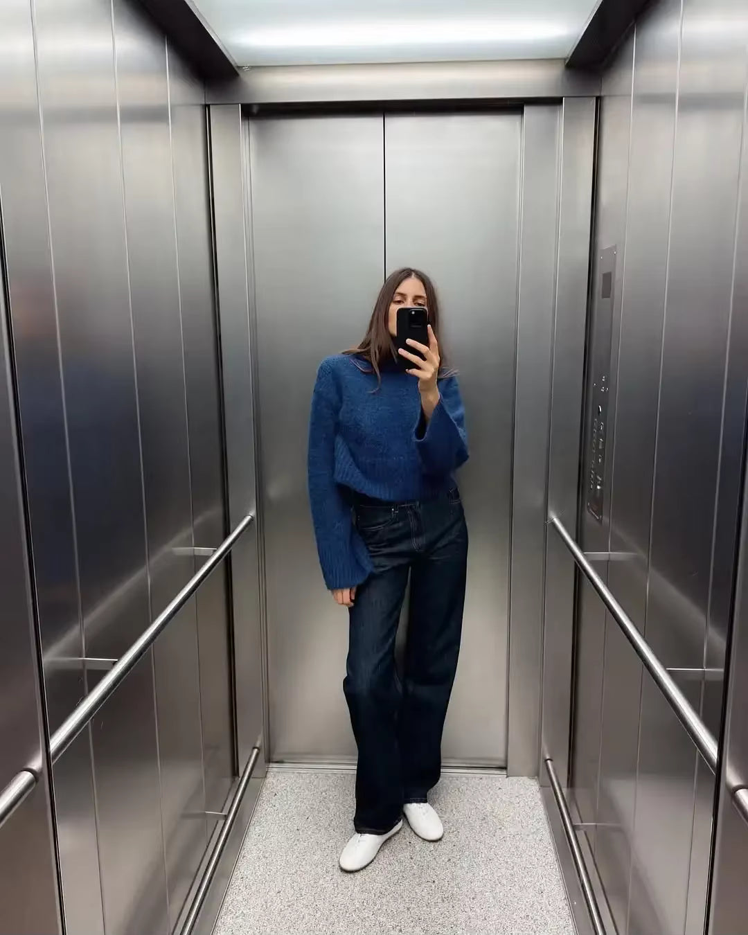 vrouw draagt blauwe gebreide cropped coltrui met wijde mouwen in spiegelselfie