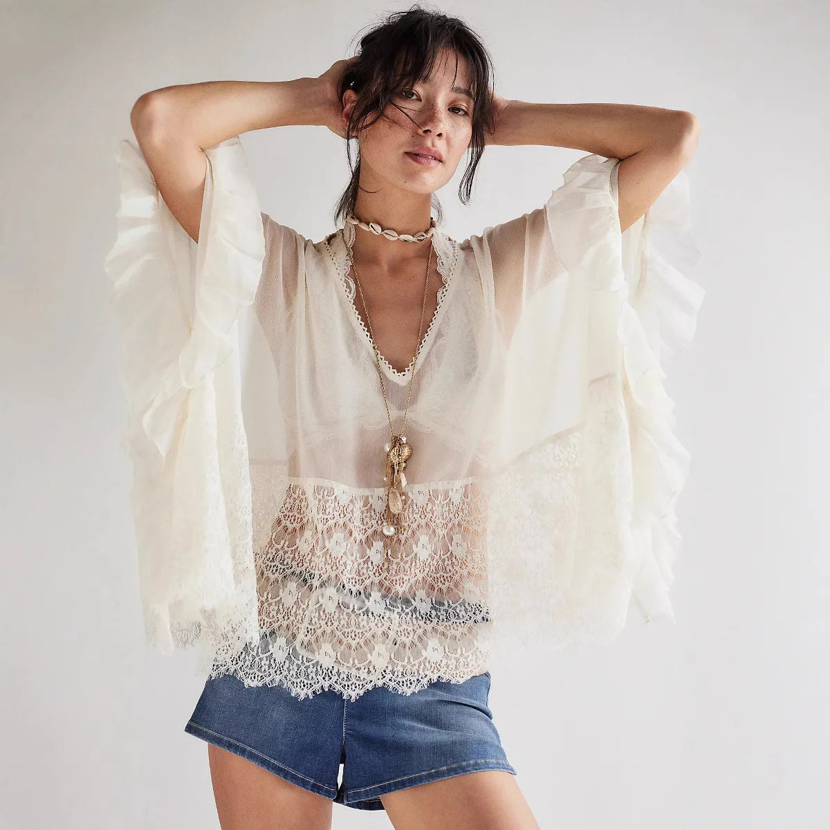 Witte blouse met kant en wijde mouwen, gecombineerd met denim shorts en strandaccessoires