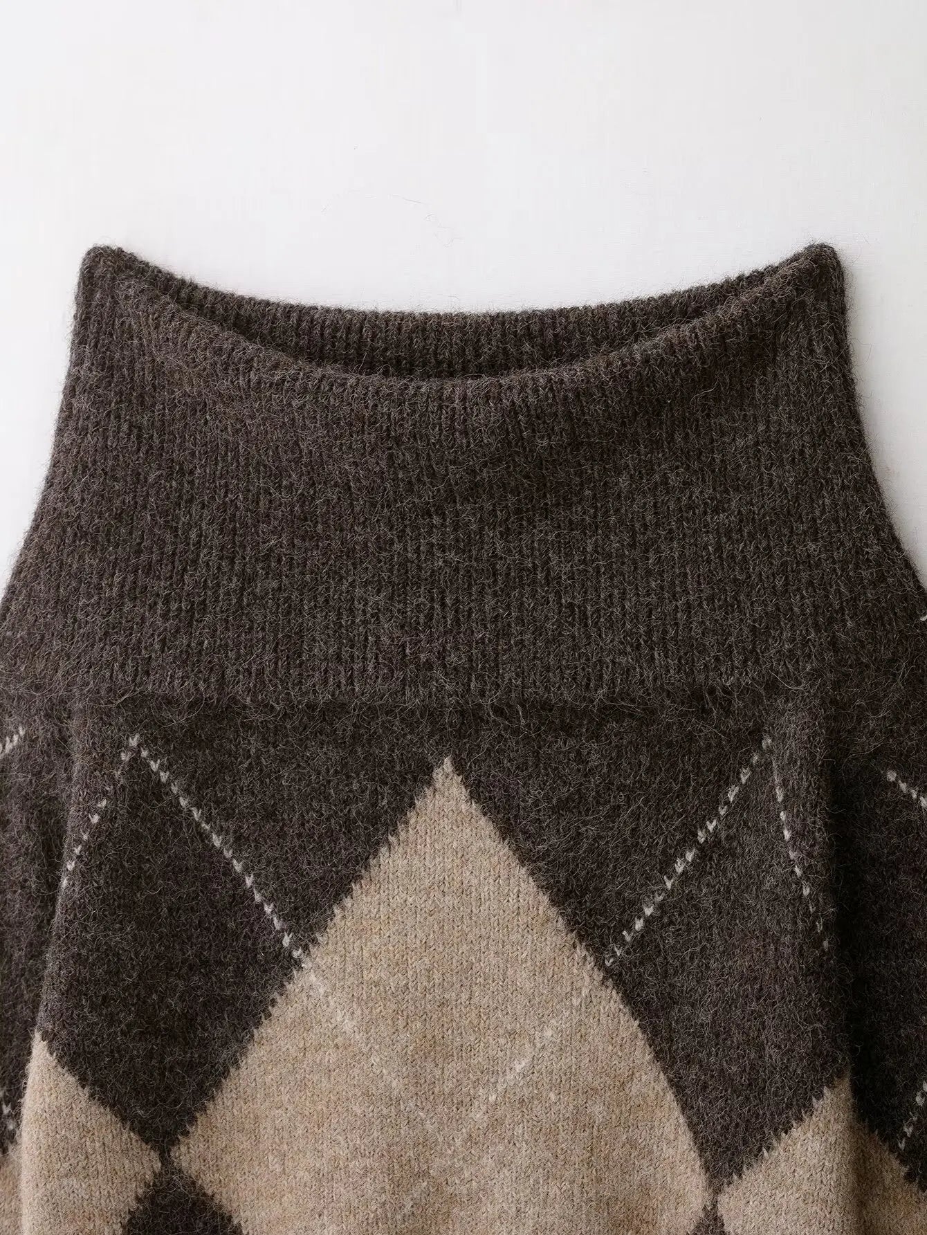 close-up van argyle patroon in bruine en beige tinten op off-shoulder trui