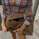 Grote suède tas met zilveren eyelets gedragen met winterjas