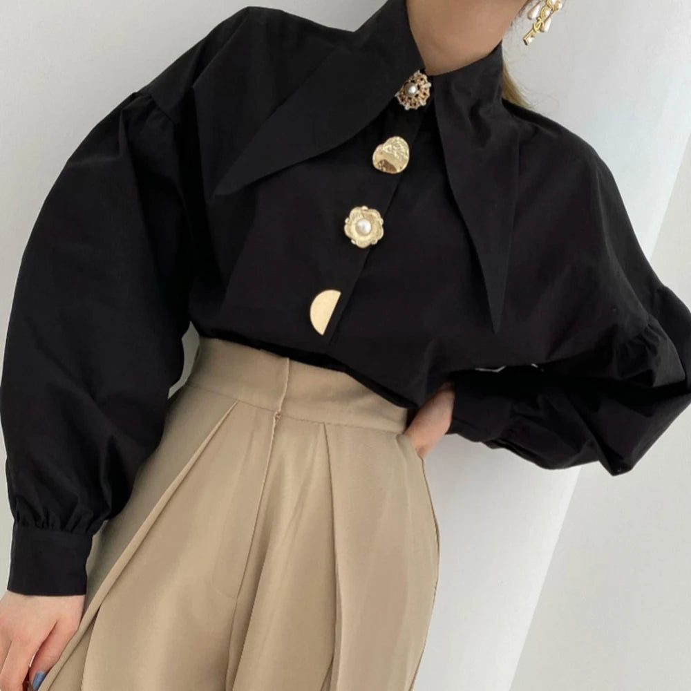 close-up van zwarte blouse met ballonmouwen en luxe knopen