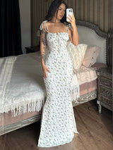 Witte maxi-jurk met zwarte bloemenprint en vrouwelijke pasvorm, binnenshuis gefotografeerd
