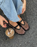 zwarte mesh mary jane flats onder blauwe jeans op straat