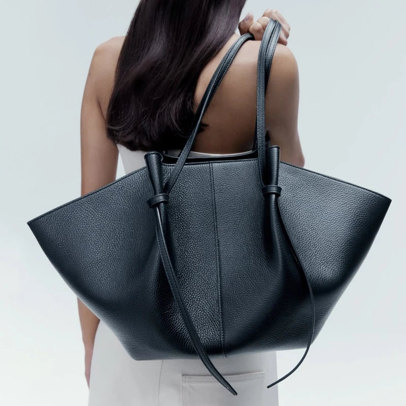 vrouw draagt zwarte totebag over schouder met minimalistische outfit