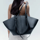 vrouw draagt zwarte totebag over schouder met minimalistische outfit