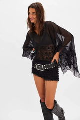 Zwarte blouse met kant en wijde mouwen, gecombineerd met korte rok en brede riem
