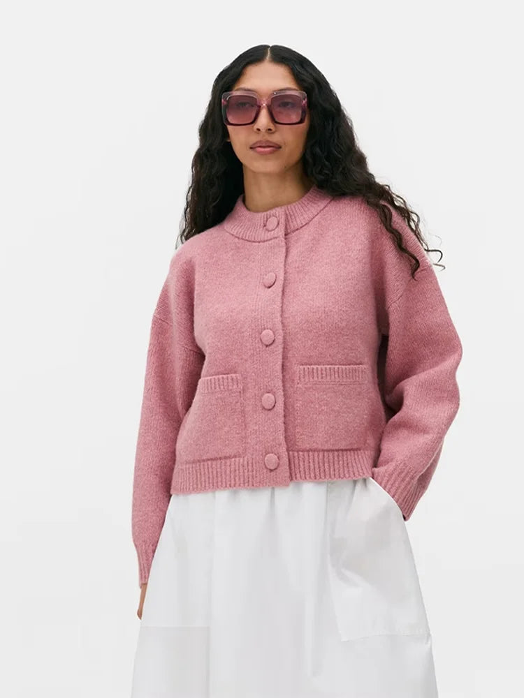 vrouw draagt roze gebreid vest met ronde hals en grote knopen