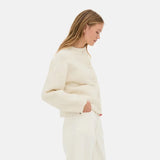 crème vest gedragen door vrouw met witte broek, zijaanzicht