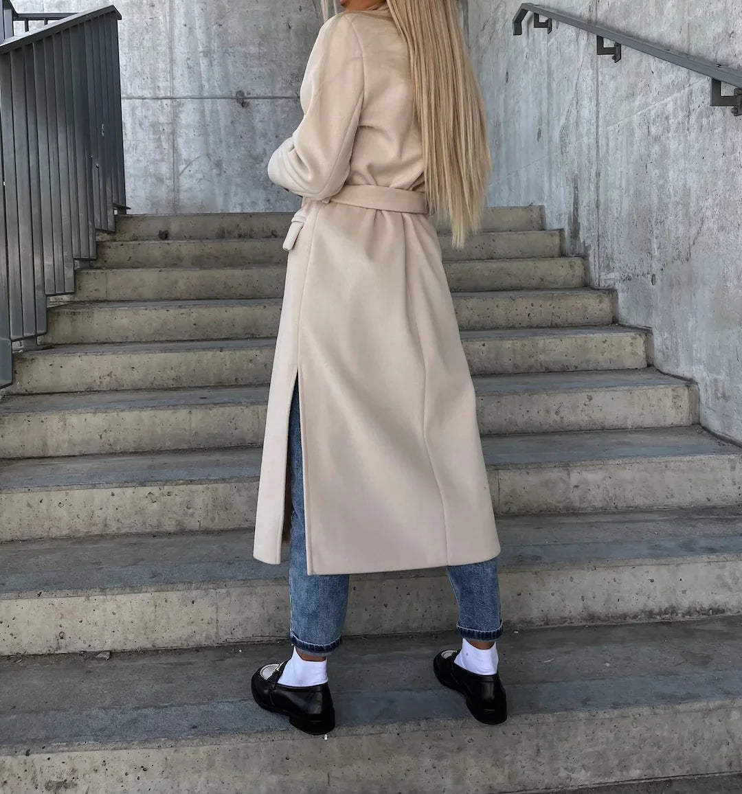beige double-breasted manteljas met zwarte loafers en jeans