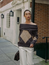 vrouw draagt off-shoulder gebreide trui met groot argyle patroon in bruin en beige