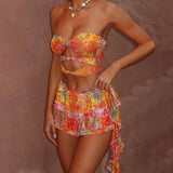 kleurige bandeau set met cut-out top en gelaagde minirok, bandeau crop top met tropische print en ruches rok, kleurrijke zomerset met bandeautop en ruches, zomerse outfit set met oranje roze print en strikdetail