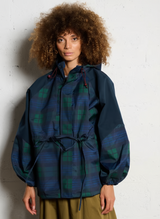 vrouw draagt blauwe regenjas met ruitpatroon en taillekoord