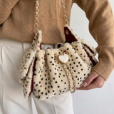 close-up beige faux fur tas met zwarte stippen en gouden hartsluiting