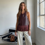 Bordeauxrode kunstleren top met franjes in daglicht, gedragen met een cremekleurige wide leg broek