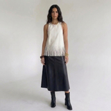Off-white kunstleren franjetop gecombineerd met een zwarte leren midirok en enkellaarsjes